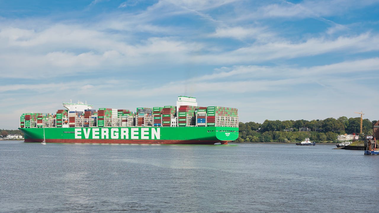 A massive cargo ship sails through Hamburg's bustling port, illustrating global trade and commerce.
